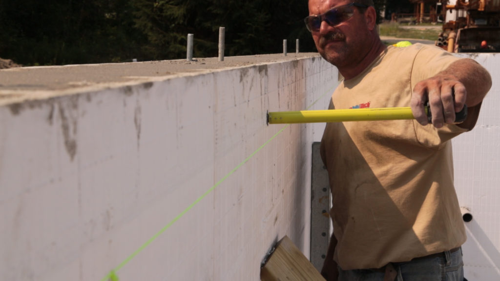 Using a string line to check the plumb of the wall after the pour