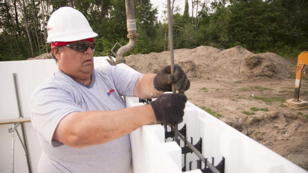 Worker wearing proper protective gear while placing vertical rebar