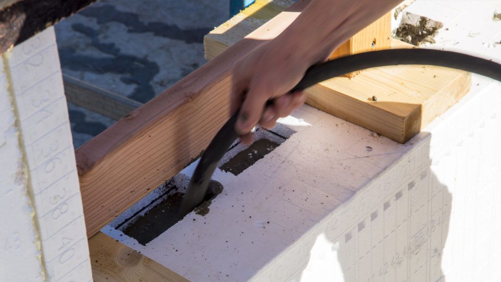 Vibrating the first lift of concrete through the inspection ports at the base of a window